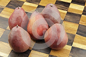 Five Red Pears on a Wooden Chessboard