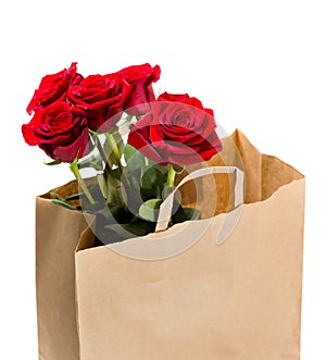 Five red roses in a paper bag on white background