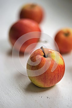 Five ripe apples, red with yellow spots, lie on a white table