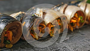 Five rolls of mackerel with vegetables on a wooden rustic table.