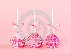 Five romantic pop cake with pink frosting on pink background.