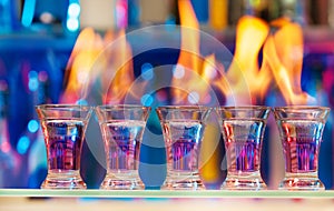 Five shot glasses with flaming cocktails