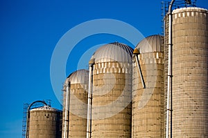 Five silos at different hights in front of a blue sky