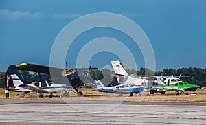 Five small aircraft next to each other are at the airport.