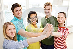 Five smiling students giving high five at school