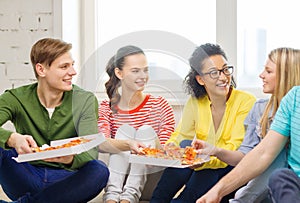 Five smiling teenagers eating pizza at home