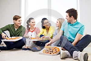 Five smiling teenagers eating pizza at home