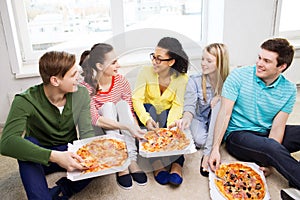 Five smiling teenagers eating pizza at home