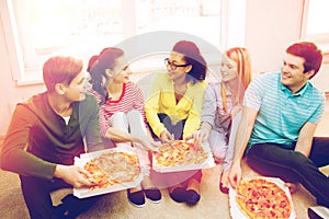 Five smiling teenagers eating pizza at home