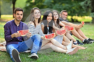 Five smiling women and men with slices of watermelon outdoors