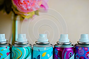 Five deodorant nozzles close up. Five colorful spray bottles with biege blurred background