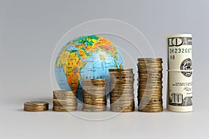 Five stacks of coins with a globe and a bundle of
