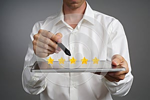 Five star rating or ranking, benchmarking concept. Man with tablet PC assesses service, hotel, restaurant