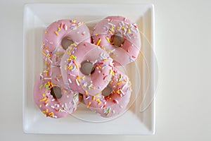 Five Sweet Pink Doughnuts Confection Served on a Square White Pl