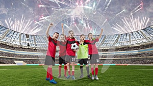 Five teenage soccer players celebrating victory on a soccer field