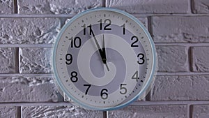 It is five to twelve, the clock is ticking. White Watch shows the time 5 before 12. Close up to a wall clock, with five minutes to