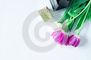 Five tulips of white and pink color and small gift box of gold color and brown gift bag on a white background with place for text.