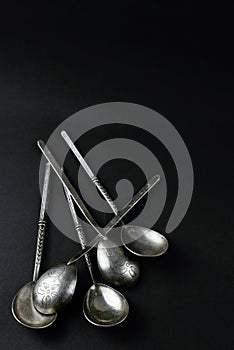 Five vintage silver teaspoons on black background