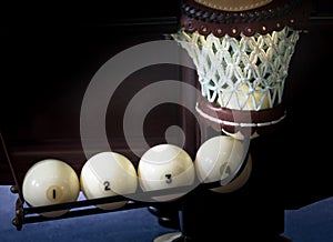 Five white billiards balls scored in the hole, the light in the hole, the background close-up