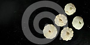 Five white pattypan squash on black marble like board, view from above, wide banner with space for text left side