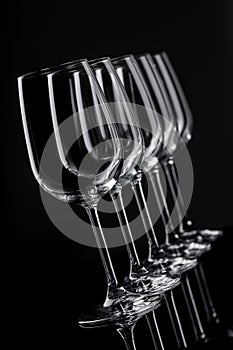 Five wine glasses in row tilted in perspective on black background