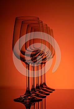 Five wine glasses silhouette in perspective row concentric on red-orange background