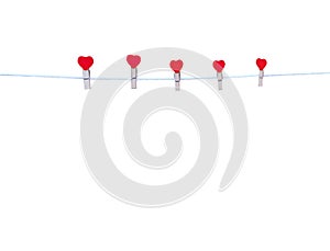 Five wood clothes pins in red heart shape patterns hanging on white string isolated on white background , clipping path