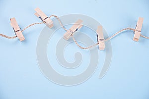 Five wooden clothespins on a rope on blue background