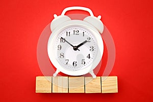 Five wooden cubes with space for text and alarm clock on red background. Time is money concept. Time-limit. Business