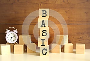 Five wooden cubes stacked vertically to form the word BASIC on a brown background