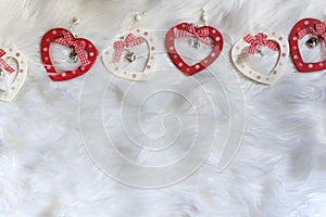 Five wooden heart shaped xmas ornaments on white soft fabric with ribbons