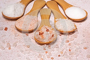 Five wooden spoons with different types of salt are spread out in a fan on the table photo