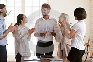 Five workmates standing in boardroom applauding congratulating team leader