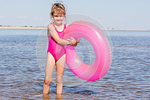 Five-year girl in pink bathing suit standing with swimming laps in the river