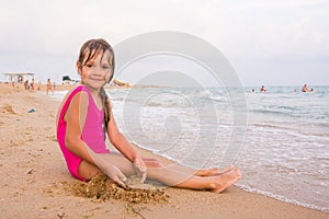 Five-year girl sitting on beach seaside