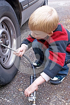 Five year old child filling a car tire with air.