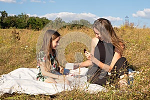 A five-year-old daughter gives a gift to her mother in nature in the summer field. Mother& x27;s Day, Happy Parenthood.