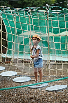 Five year old girl surmounting obstacle course in the outdoor rope park photo