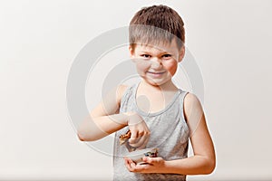 A five-year-old Russian boy dips a rolled pancake into liquid honey on a white background. Russian Maslenitsa holiday and children