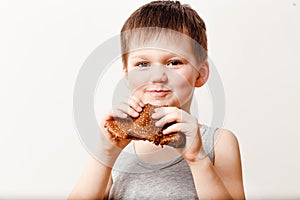 A five-year-old Russian boy in a gray t-shirt eats an oil pancake on a white background. Maslenitsa