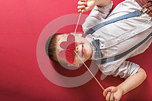 Five year old smiling boy holding a red heart on eays  symbol of love, family, hope. Backgrounds for cards on Valentine`s Day or