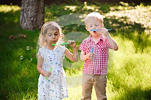 Five years old caucasian child girl and boy blowing soap bubbles