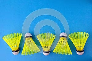 Five yellow shuttlecocks on a blue background with copy space