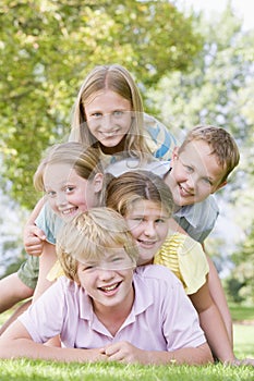 Five young friends piled on each other outdoors