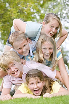 Five young friends piled on each other outdoors