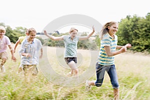 Five young friends running in a field smiling