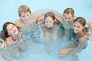 Five young friends in swimming pool smiling