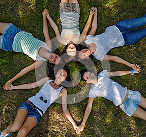 Five young ladies lounging on grassy lawn