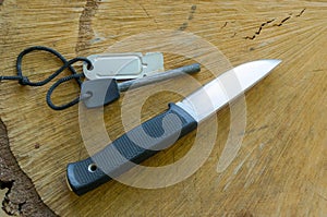 Fix knife with firestone on wood background.