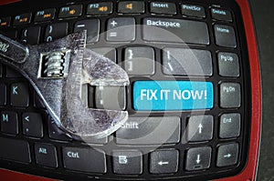 Fix it now blue button on a dirty computer keyboard with wrench tool. Fish eye effect.